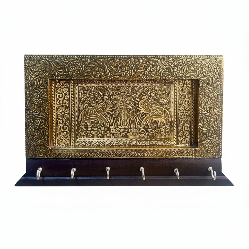 Decorative wall key holder with intricate brass design on a white background