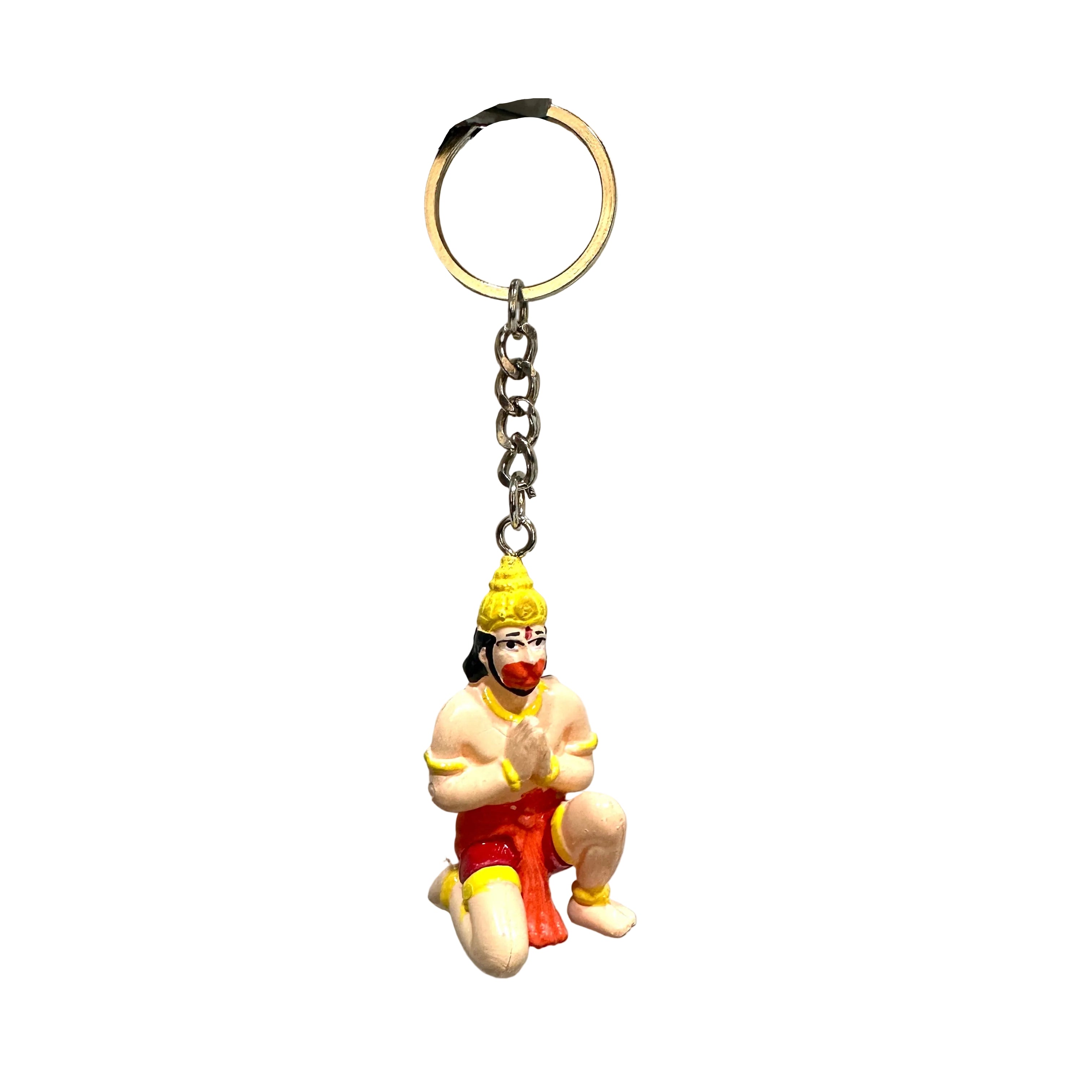 Keychain with a figurine of a sitting figure in red pants and yellow hat on a textured surface.