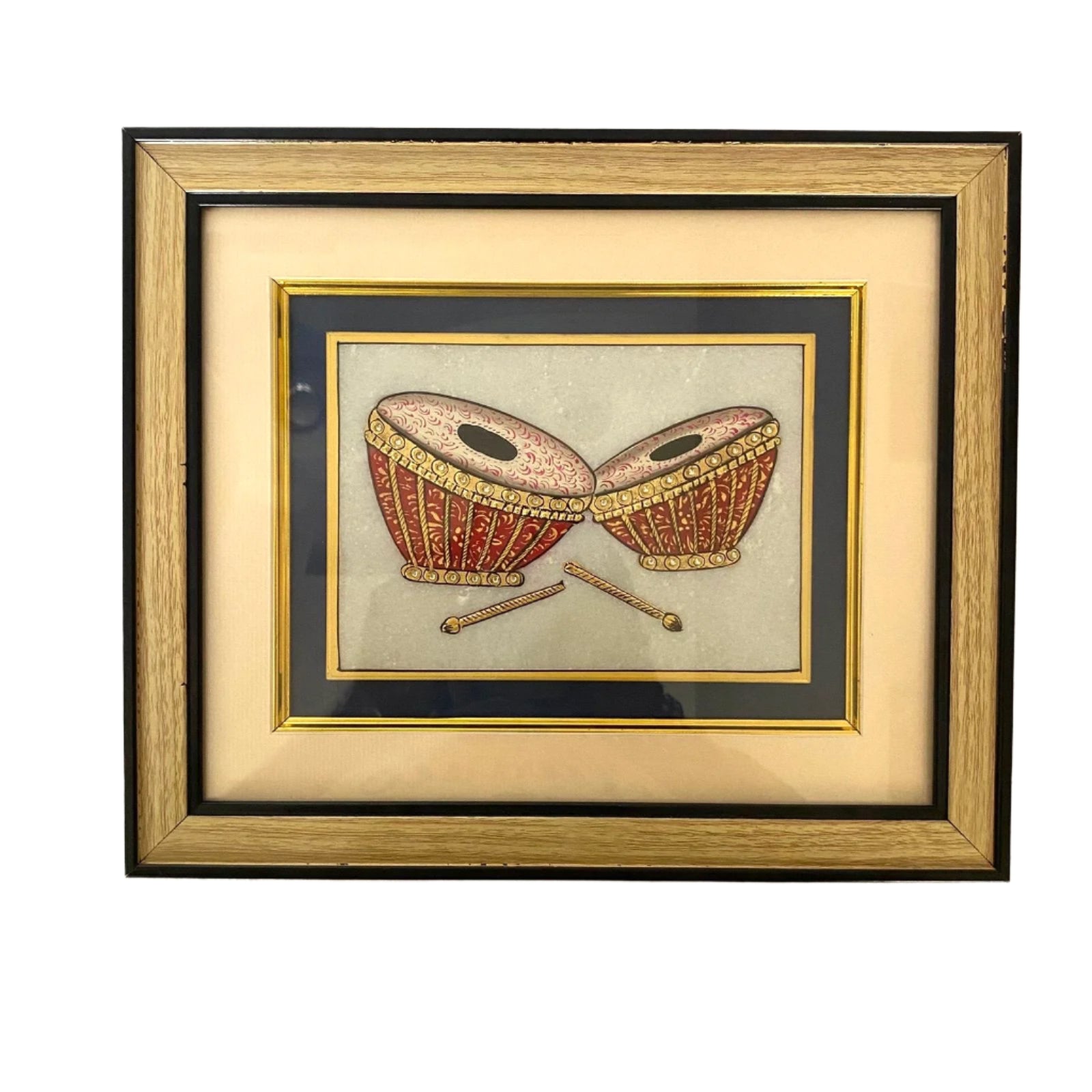 Framed artwork of two red drums with gold accents on a white wall.