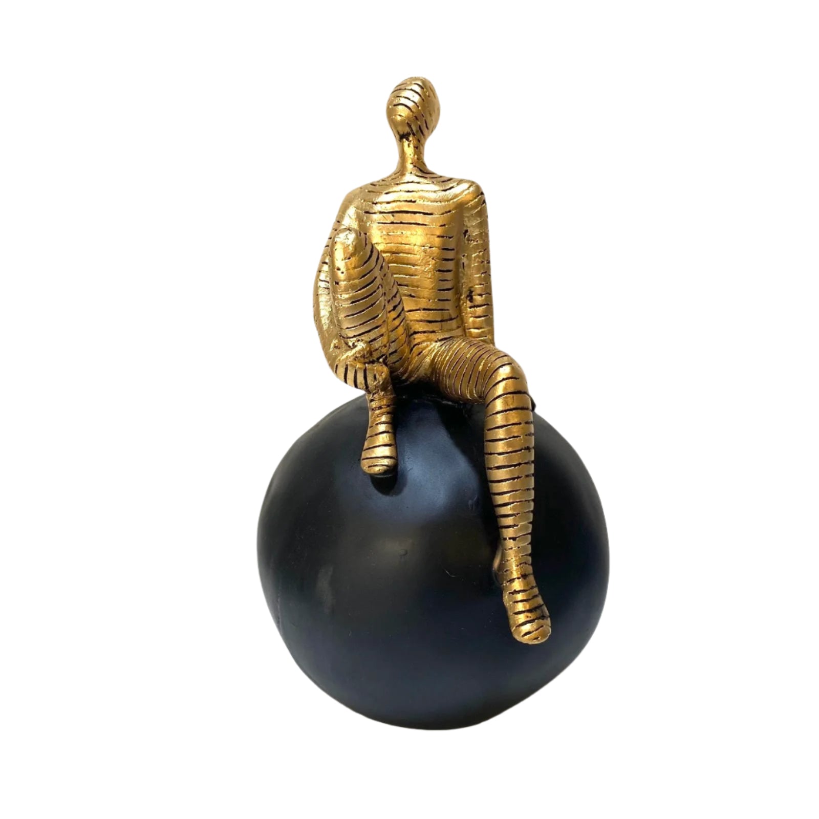 Gold sculpture of a figure sitting on a black sphere against a white background