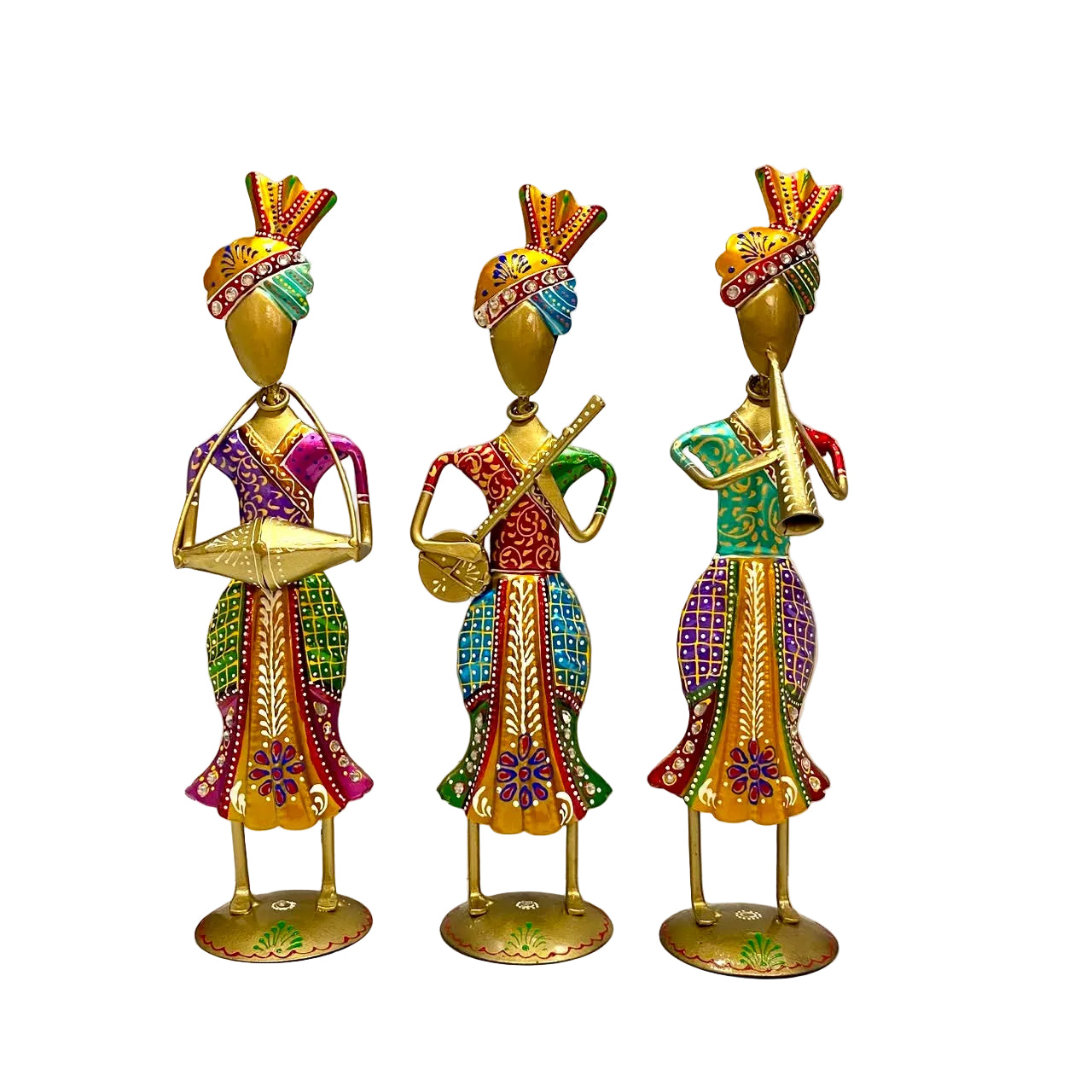 Three decorative gold-toned figurines of stylized women in colorful patterned traditional dresses, each holding musical instruments, displayed on a white surface against a white wall.
