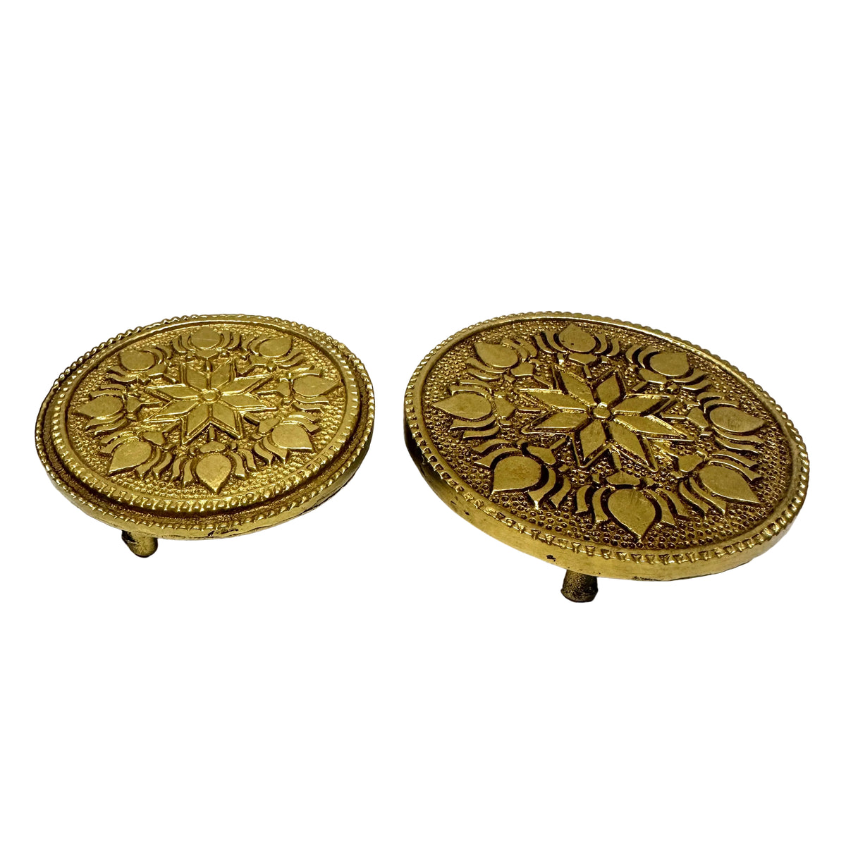 Two ornate gold circular objects on a white surface