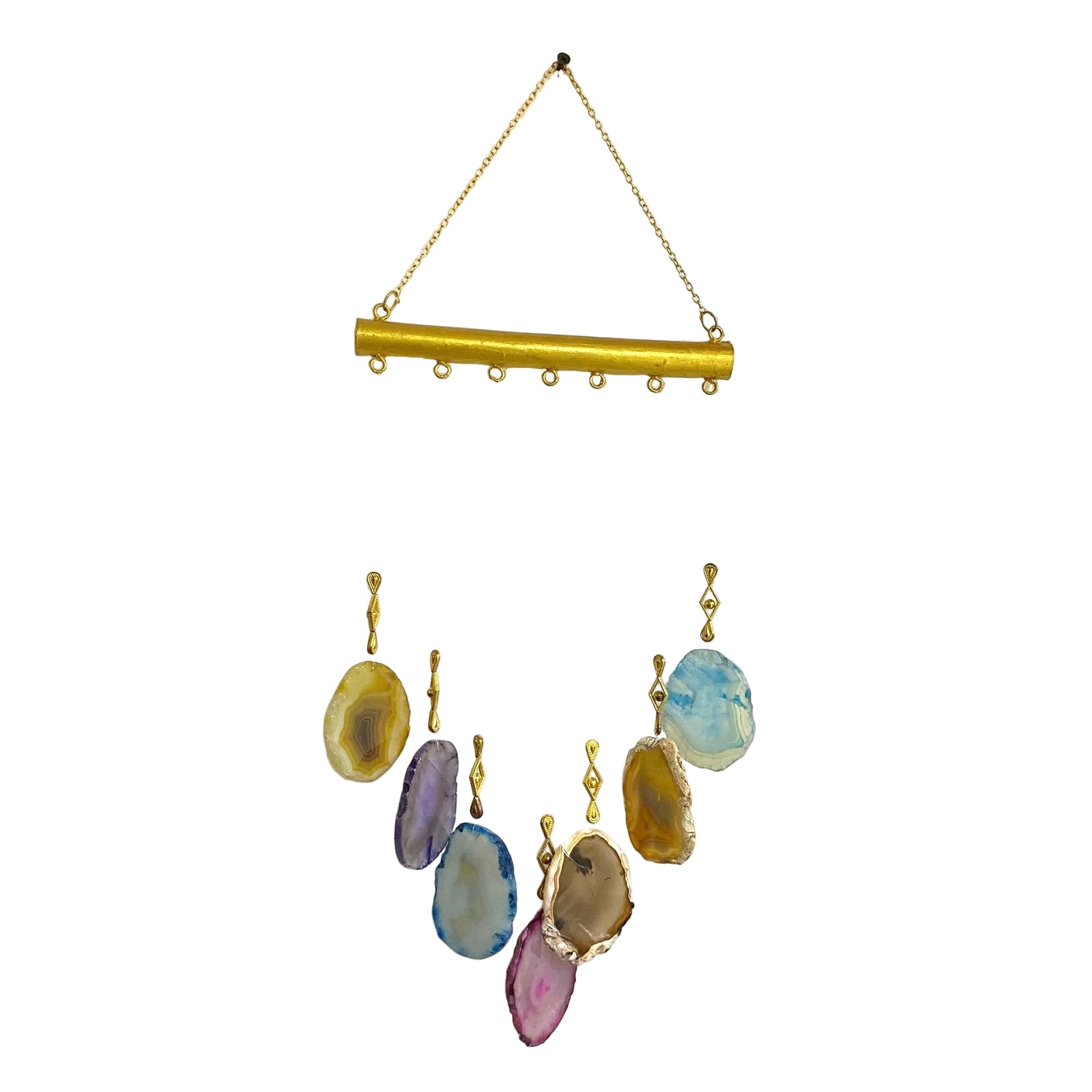 Set of colorful stone earrings hanging from a gold chain on a textured white background.
