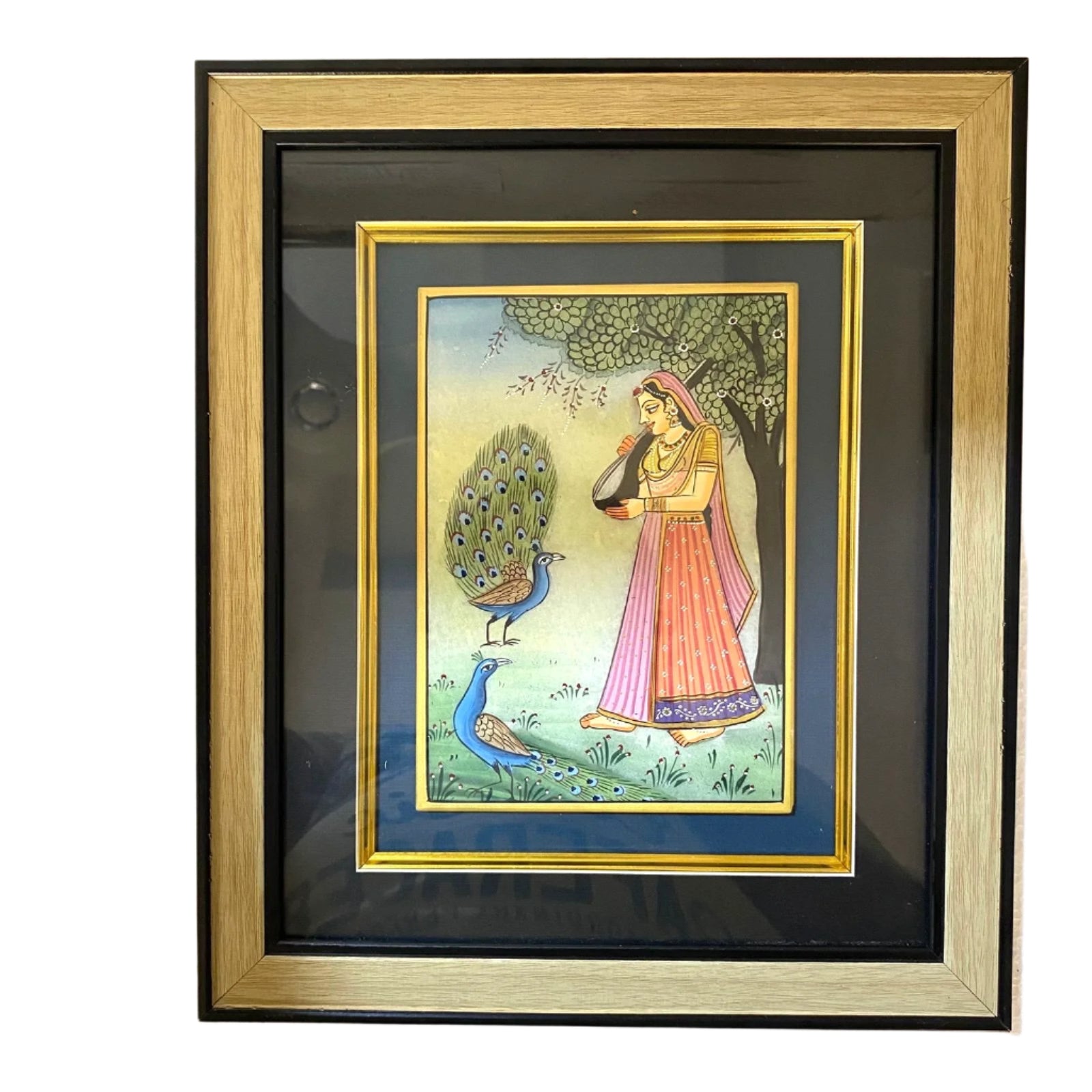 Framed artwork of a woman and peacocks on a beige wall.