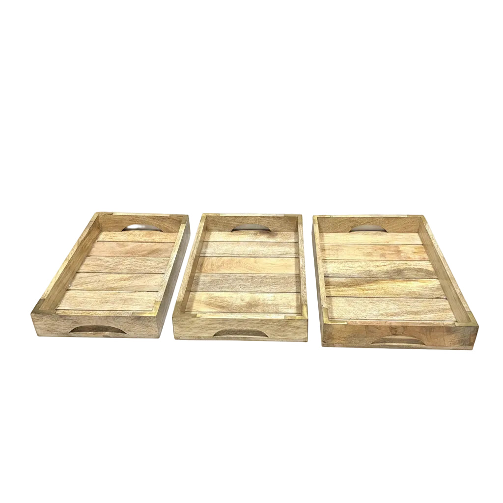 Three rectangular wooden serving trays with integrated handles, displayed side-by-side on a white table in a workshop or store setting.