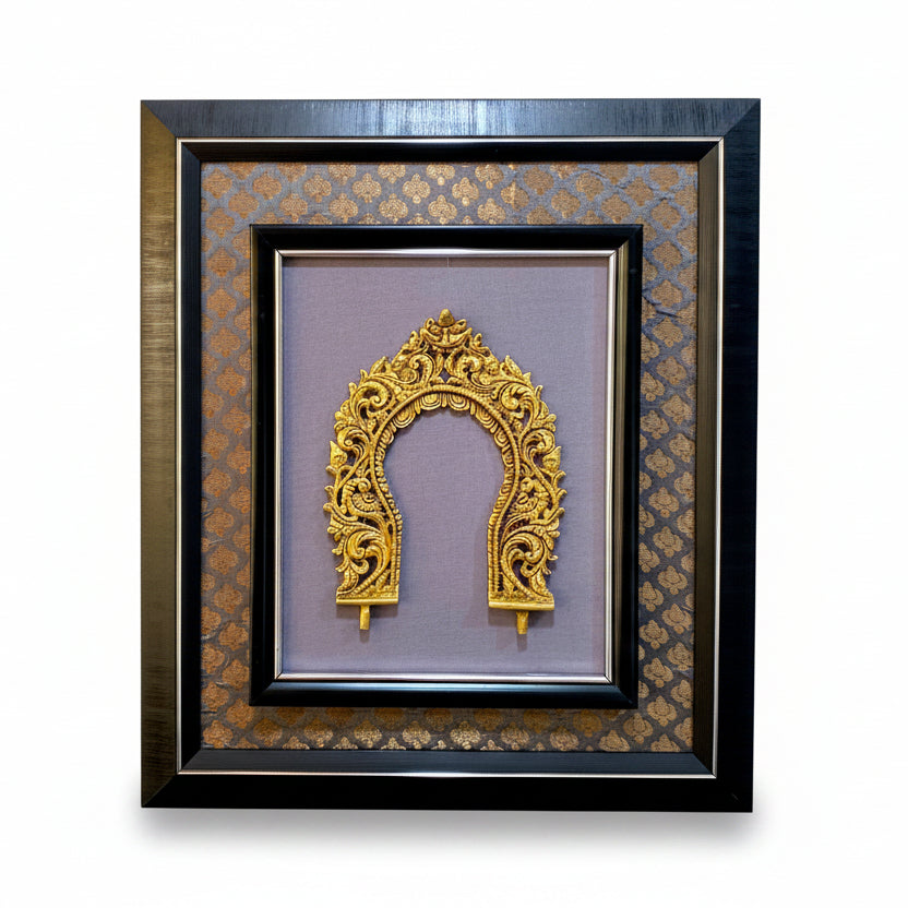A framed decorative wall art piece featuring an ornate gold arch motif mounted on a mauve-purple background, surrounded by patterned brown and gold matting and a black frame, shown hanging on a textured off-white wall.