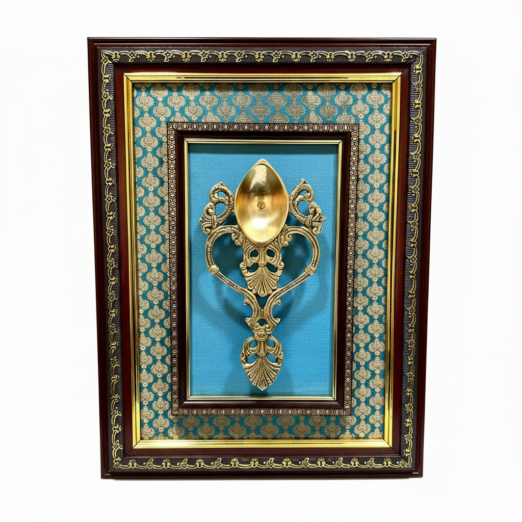 Decorative gold spoon in a framed display with blue fabric background
