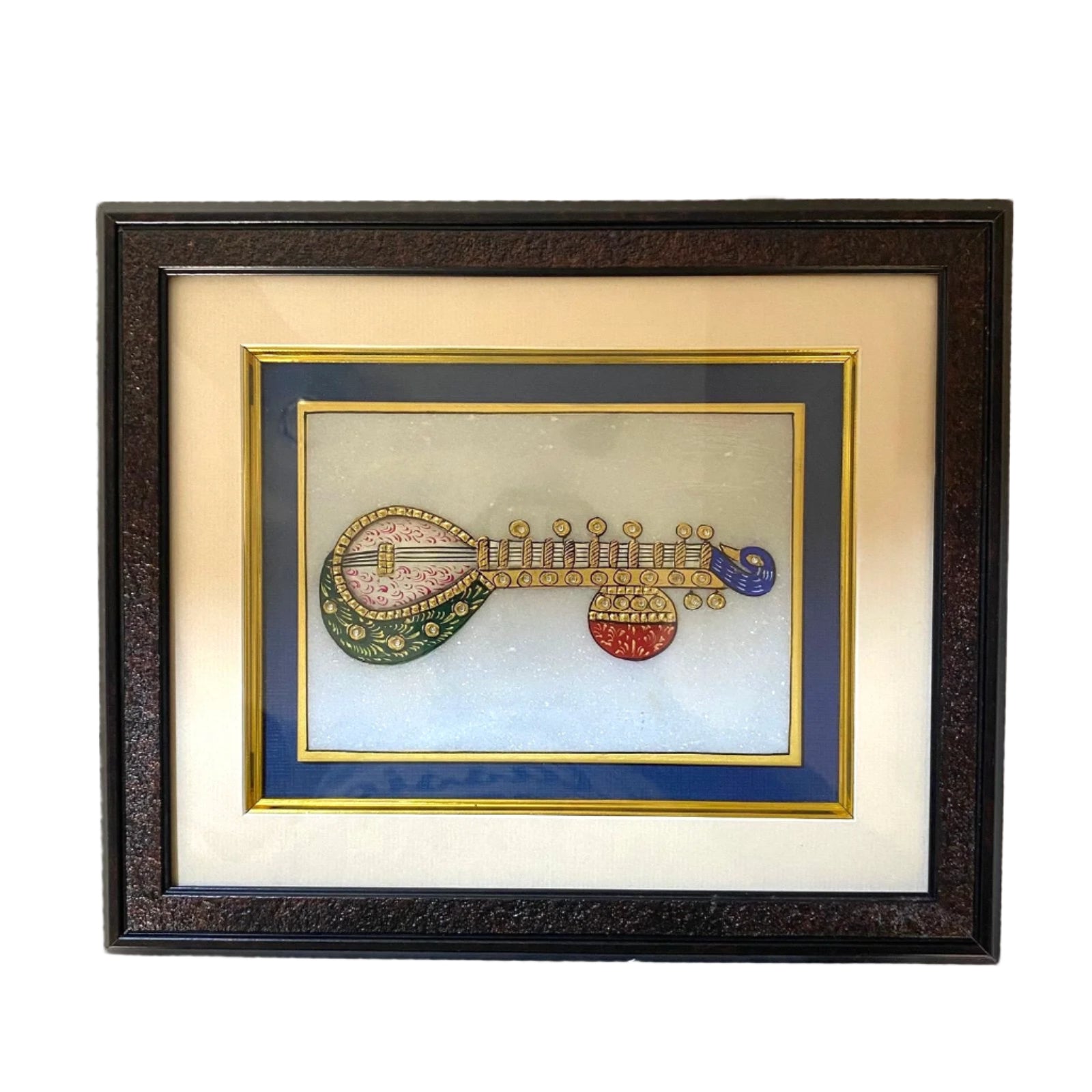Framed artwork of a decorative musical instrument on a textured wall.