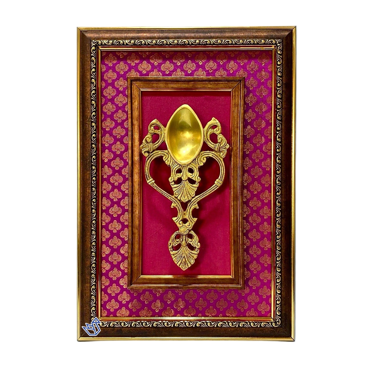 Decorative gold spoon in a framed display with pink fabric background