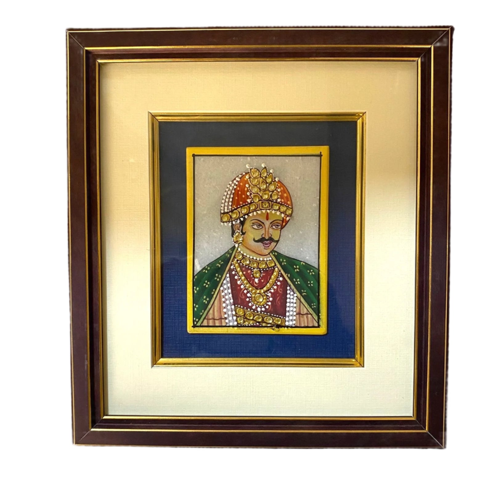 Framed artwork of a person in traditional attire with jewelry on a textured wall.