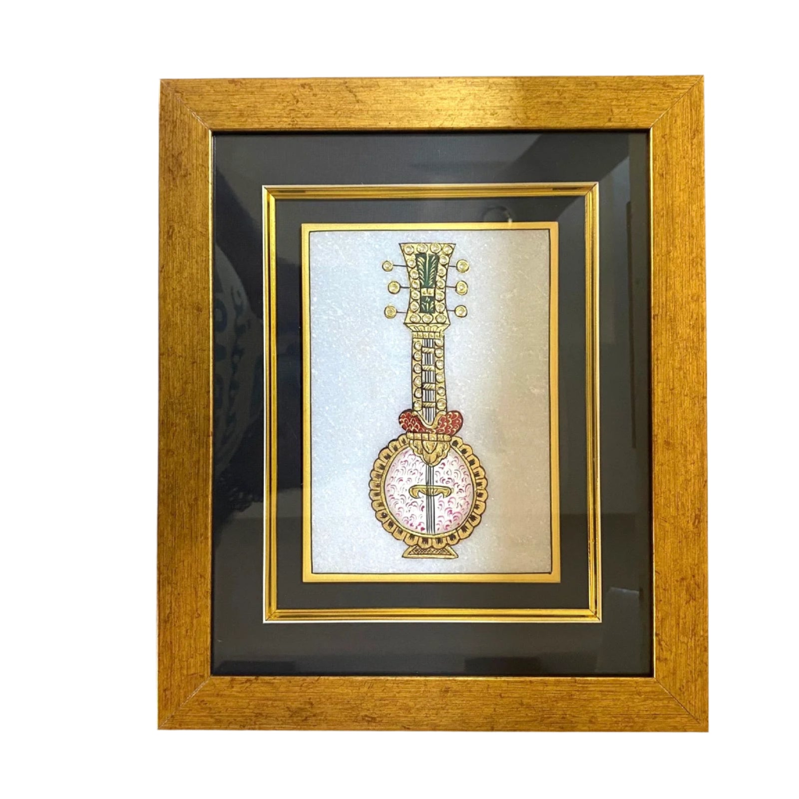 Framed artwork of a decorative instrument on a textured wall.