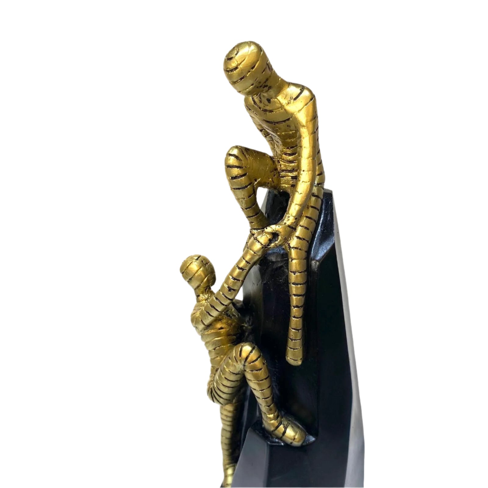 Gold figurine of a person climbing another on a white background