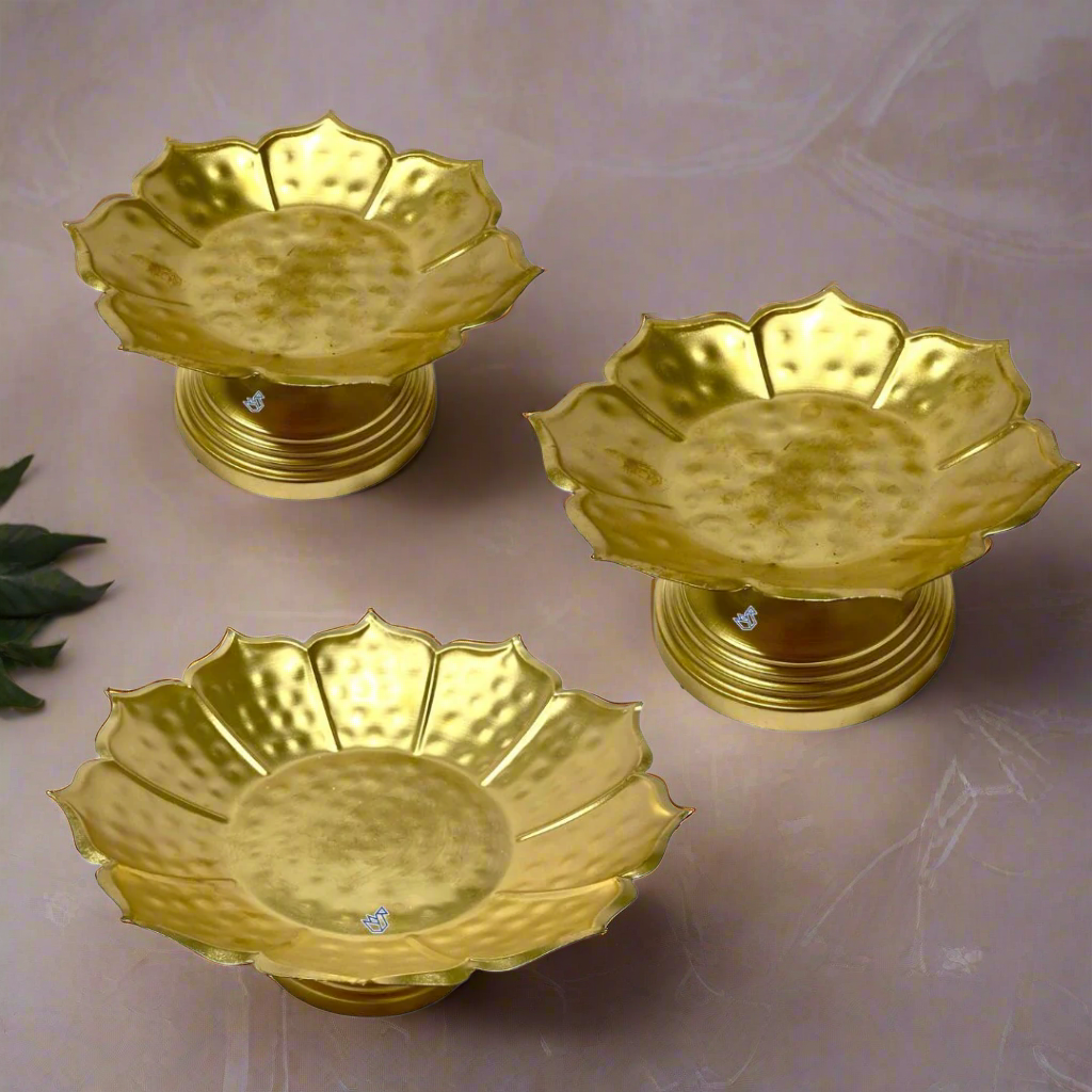 Three gold-colored leaf-shaped candle holders on a white background