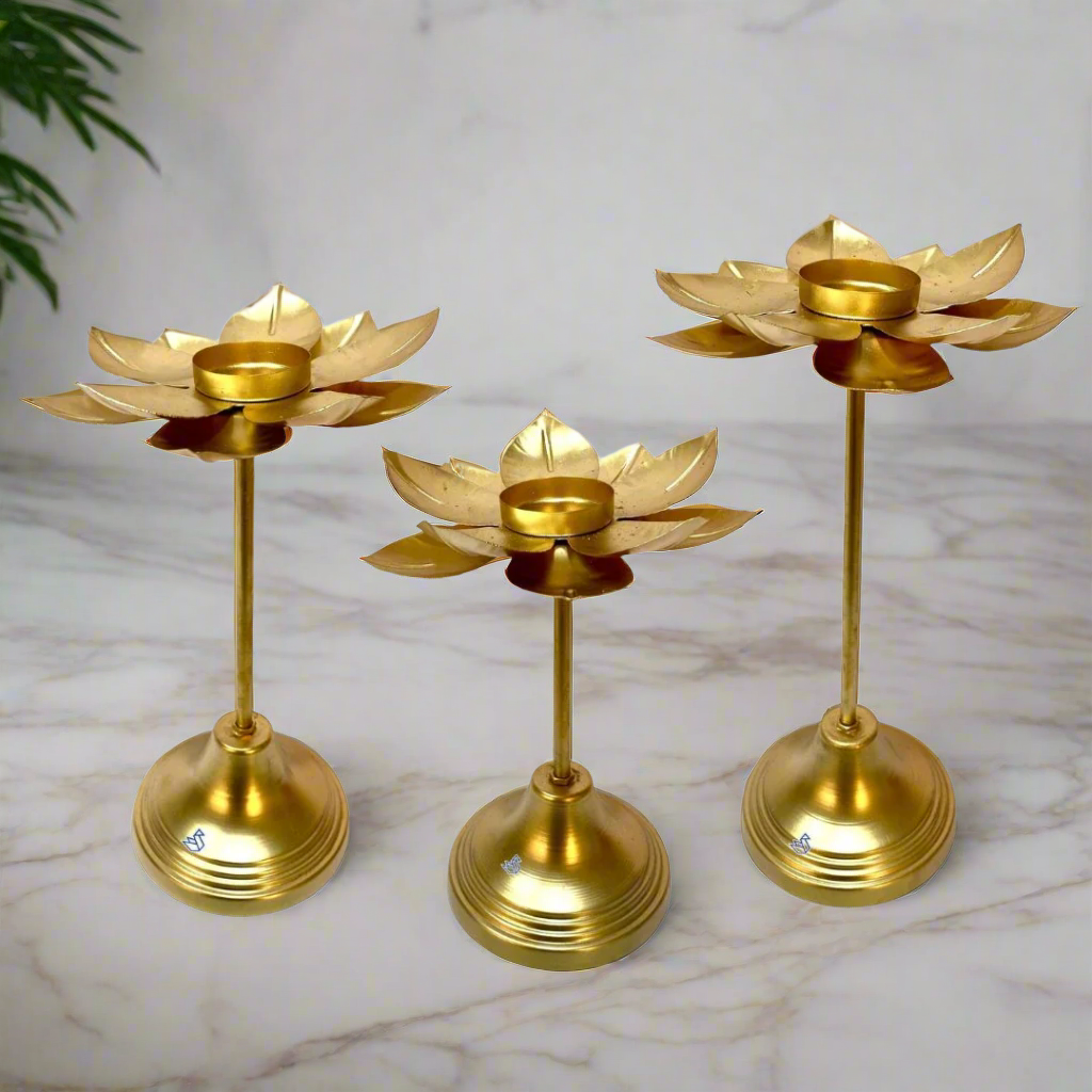 Three gold-colored lotus-shaped candle holders on a white background