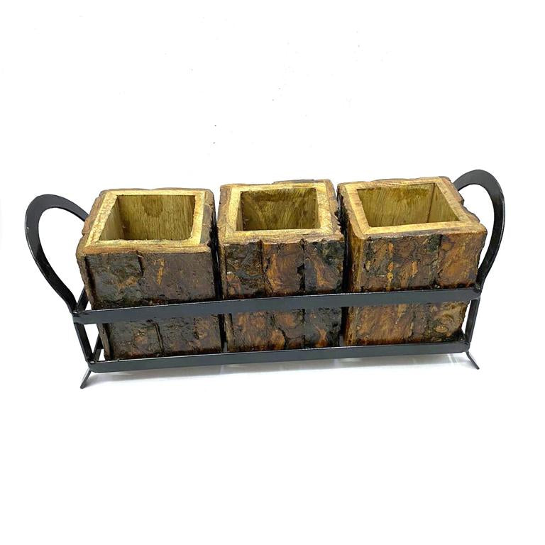 A bronze-colored metal cutlery holder with a raw finish, featuring two square compartments for holding knives and forks, supported by a black metal frame.