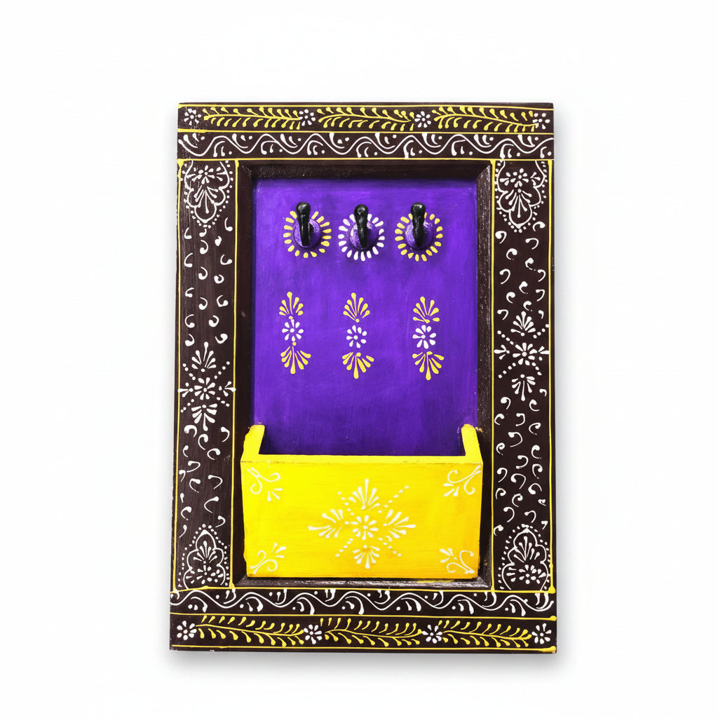 A wooden key holder with a purple background, yellow compartment, and black decorative frame with floral patterns.