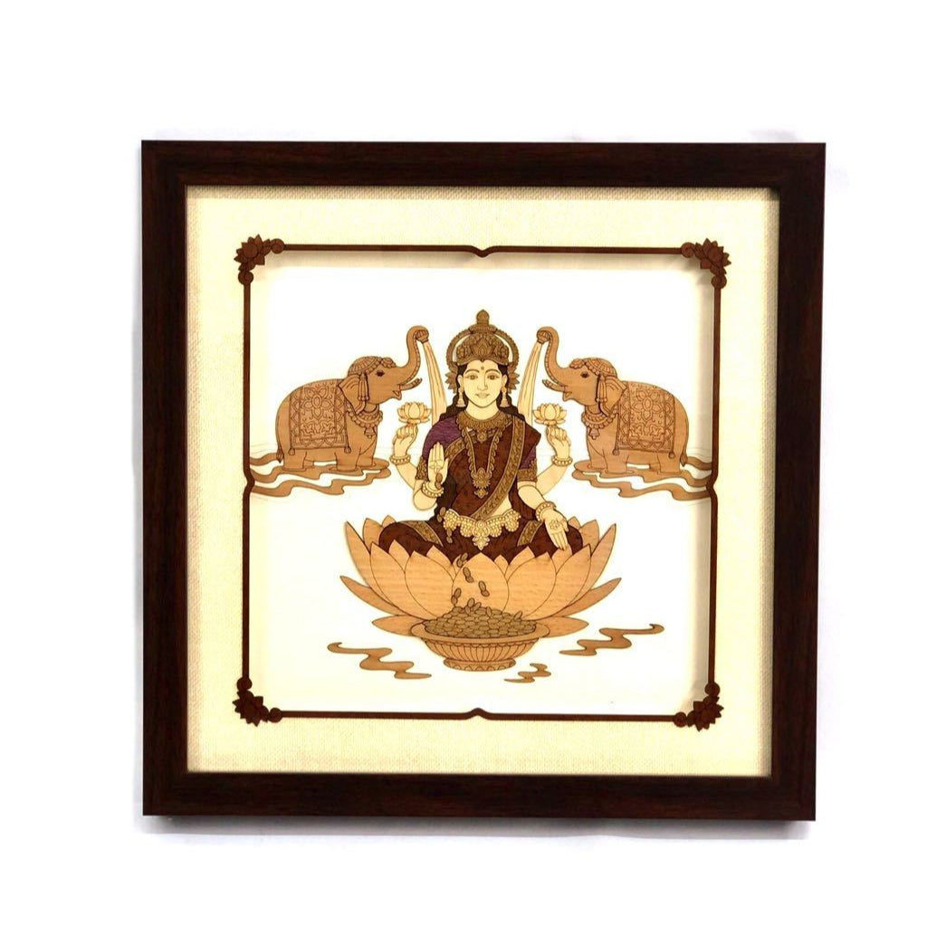 A wall hanging artwork depicting goddess Lakshmi seated on a lotus flower, with a decorative border in a wooden frame.