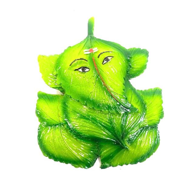 A wall-hanging decoration featuring a stylized, green-colored representation of the Hindu god Ganesha.