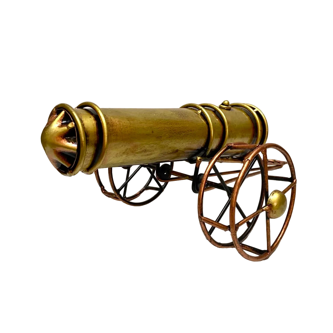 A decorative miniature cannon model made of brass and bronze metal, featuring a cylindrical barrel and four spoked wheels, photographed on a white surface against a white wall.