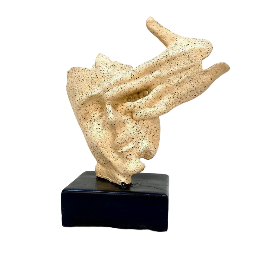 Beige abstract sculpture on a black base against a textured white wall.