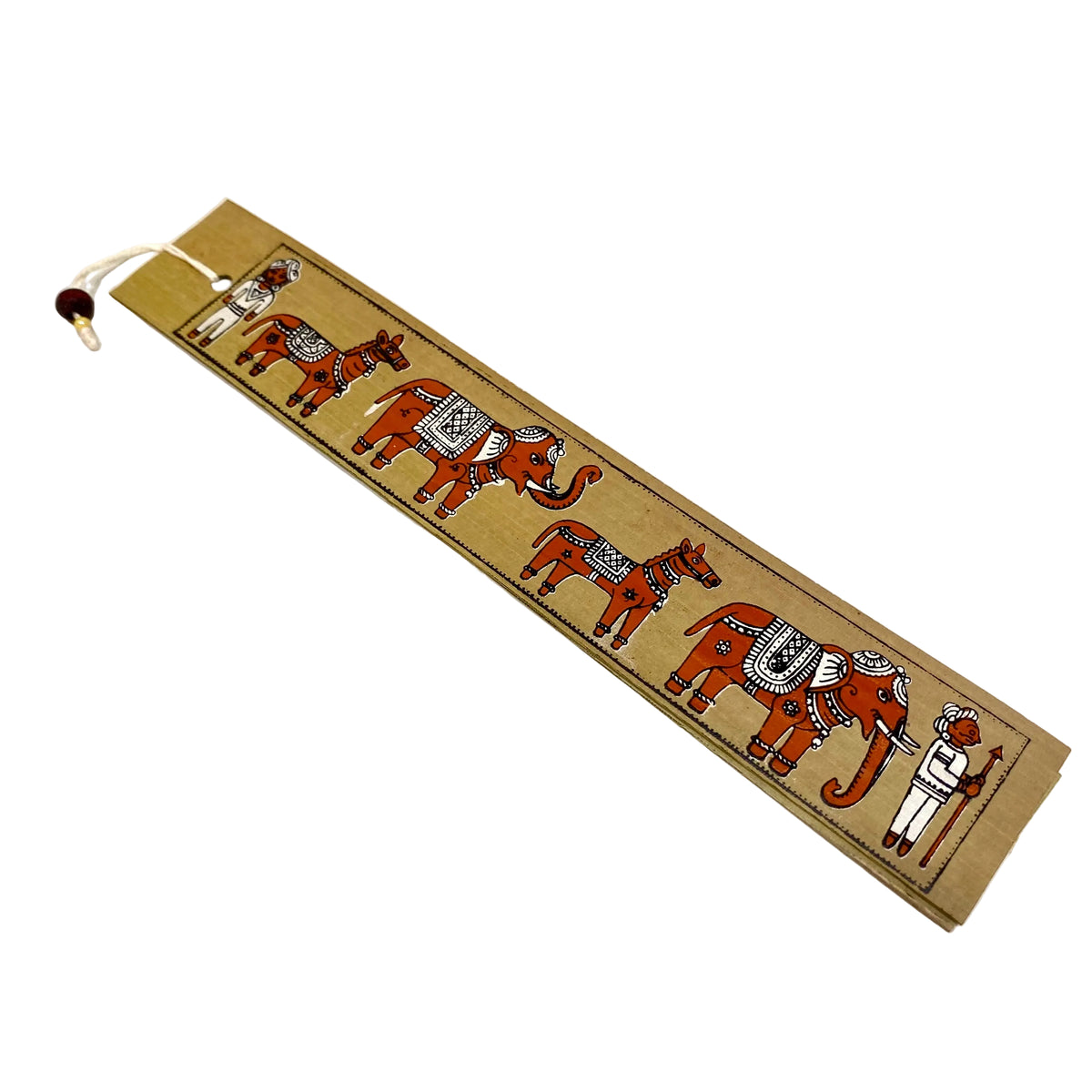 A rectangular tan paper bookmark featuring a traditional Indian hand-painted style illustration of a caravan of elephants and a shepherd, with a white string and wooden bead at the end, placed on a light off-white surface.