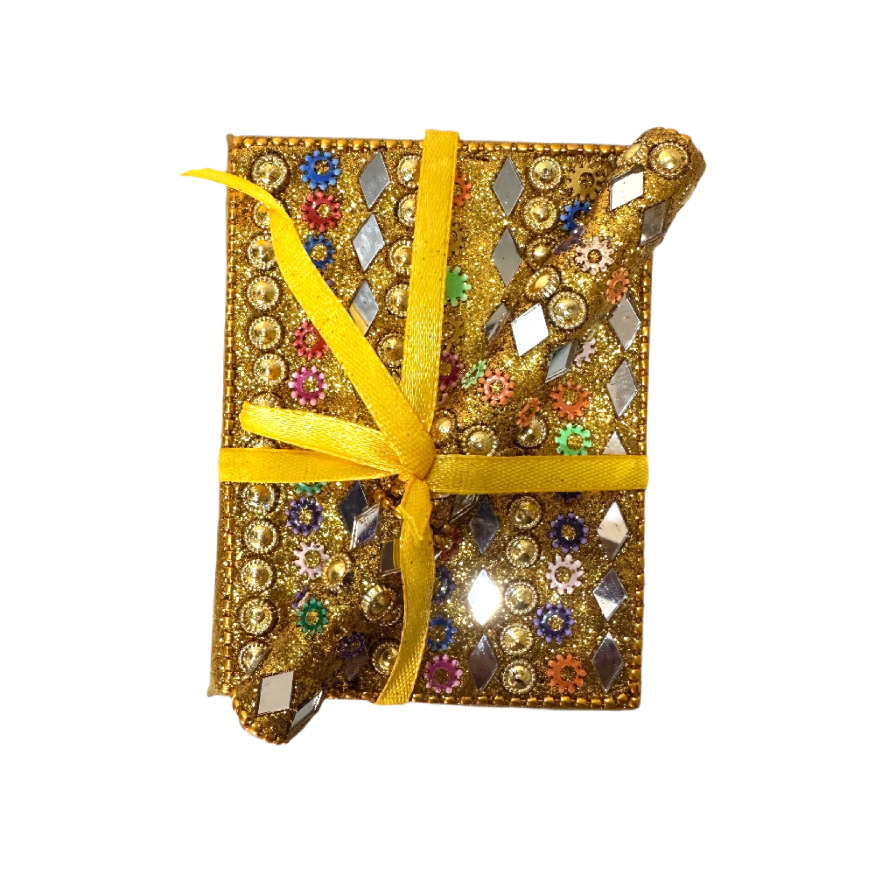 Decorative notebook with embellishments and a yellow ribbon on a white surface