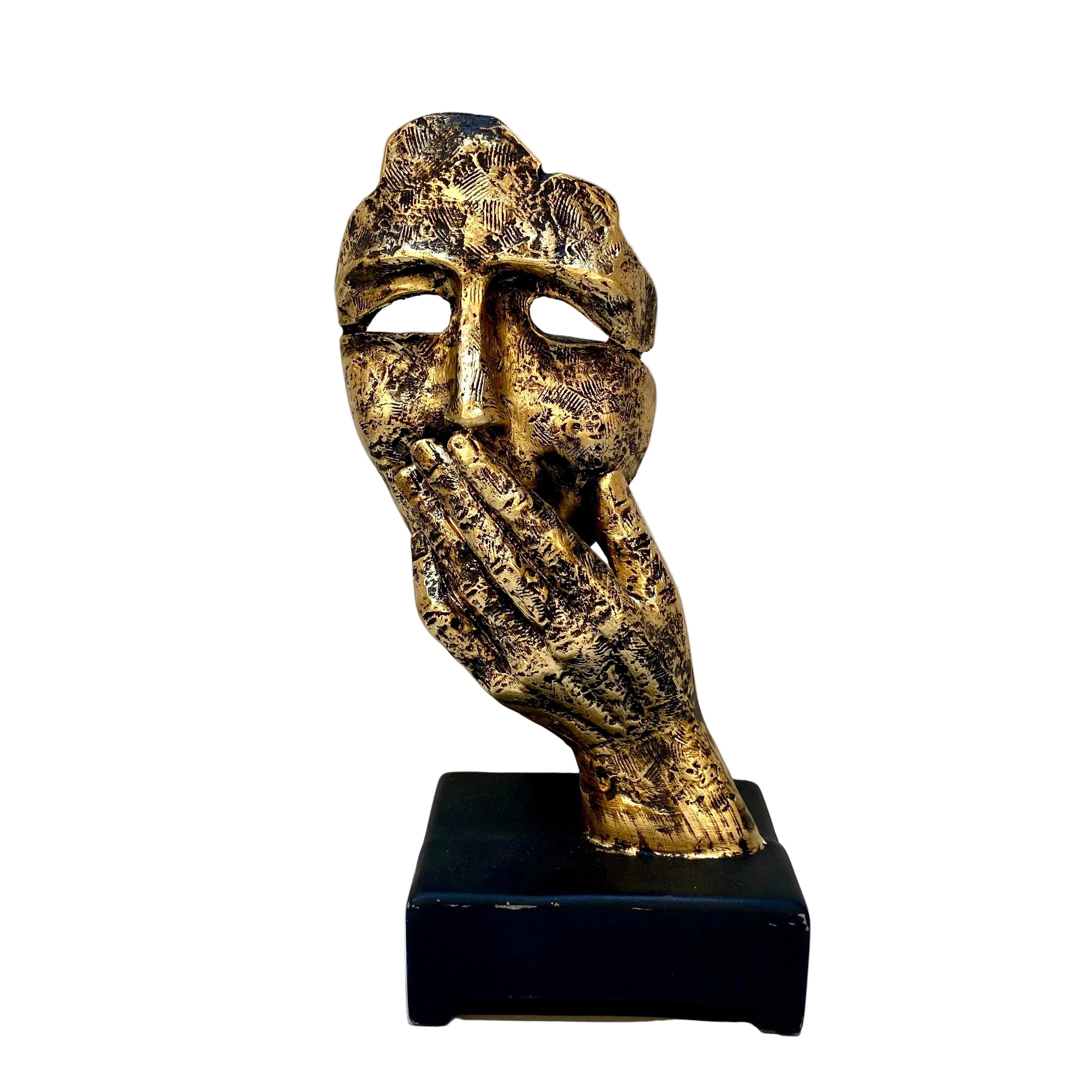 Decorative mask sculpture on a black base against a white wall