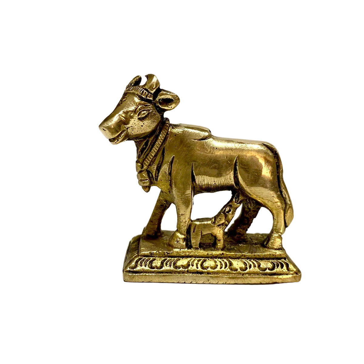 A small brass cow and calf figurine standing on a rectangular decorative base, photographed against a plain light background.