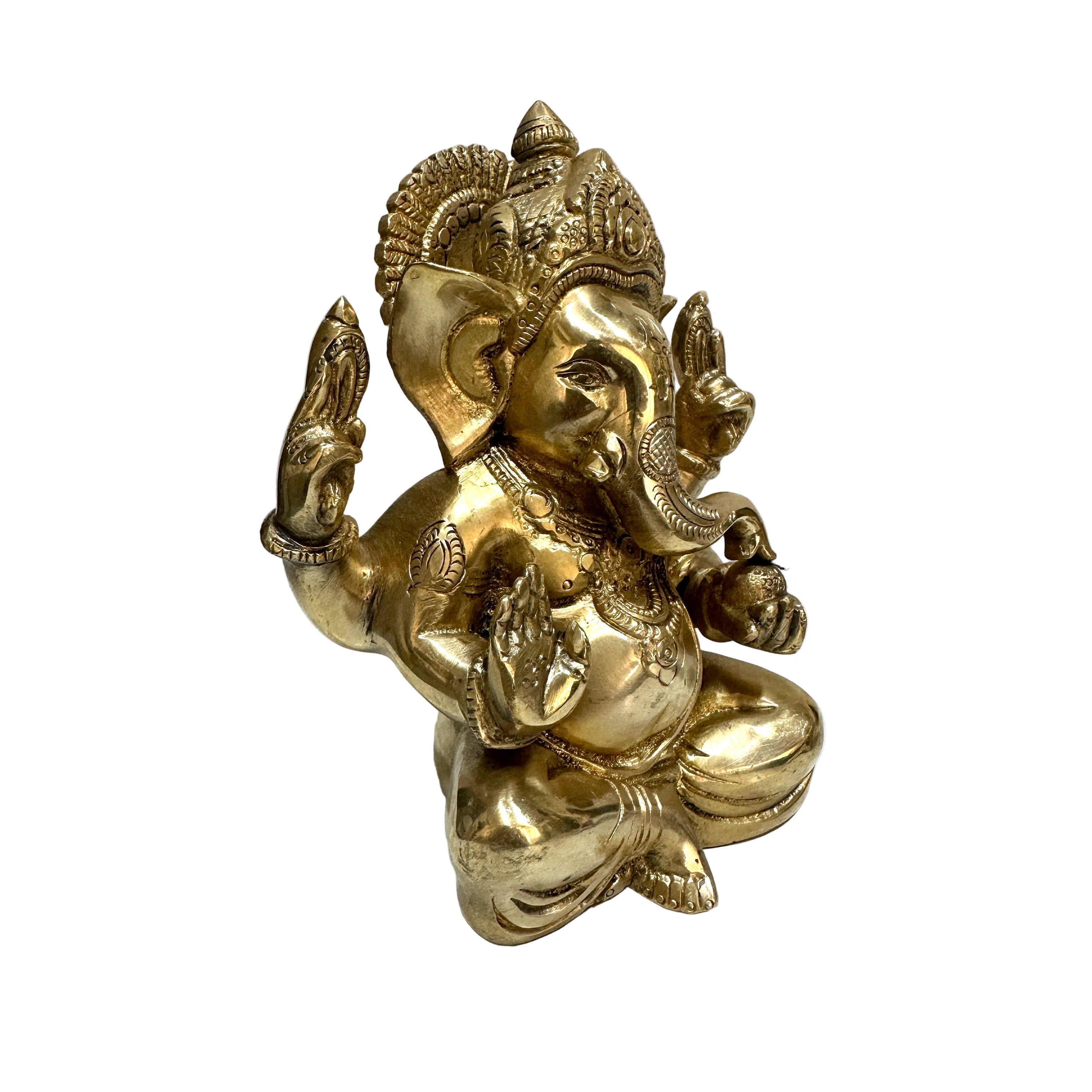 Gold-colored statue of a deity on a white surface with a white wall background