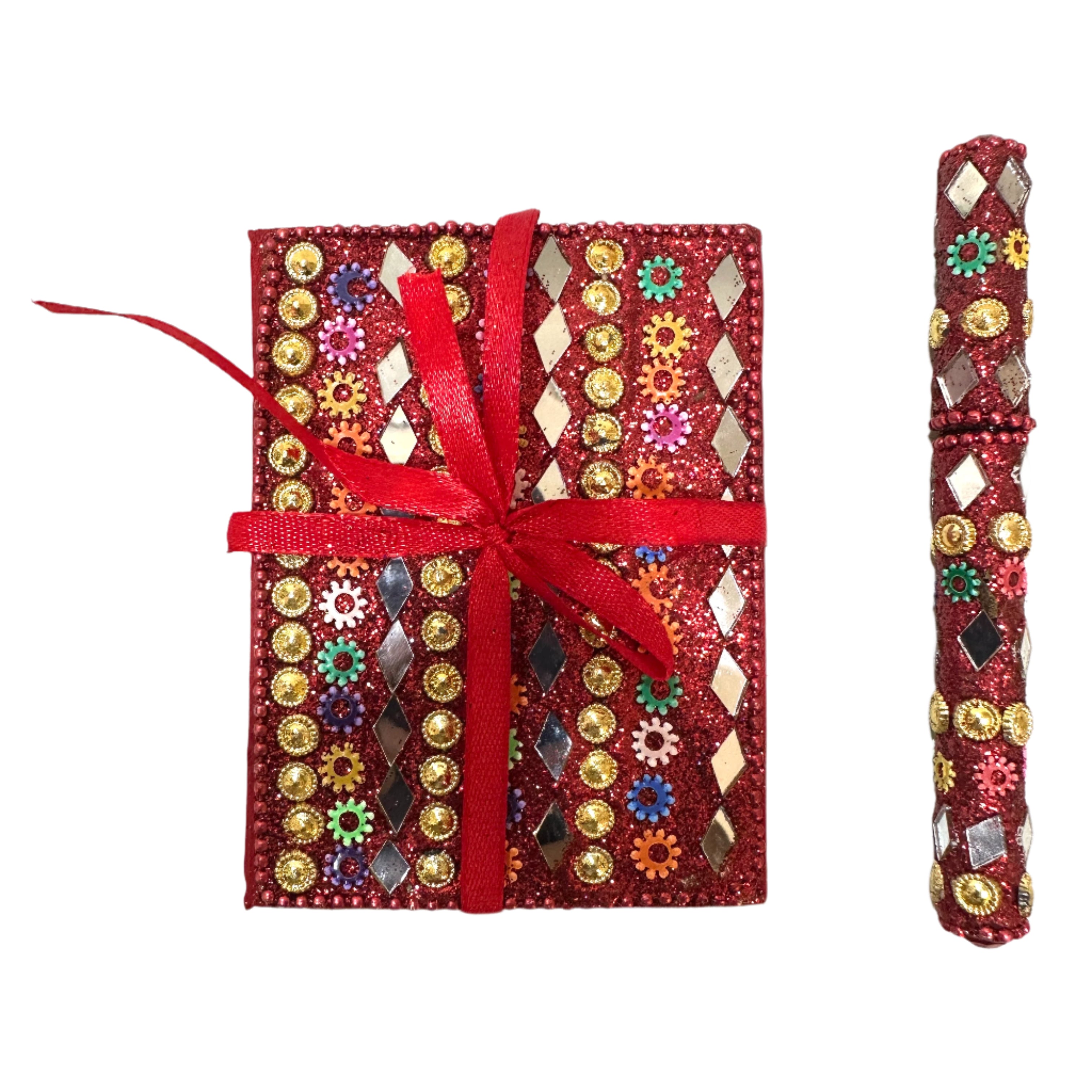 Decorative notebook with embellishments and a red ribbon on a textured white surface