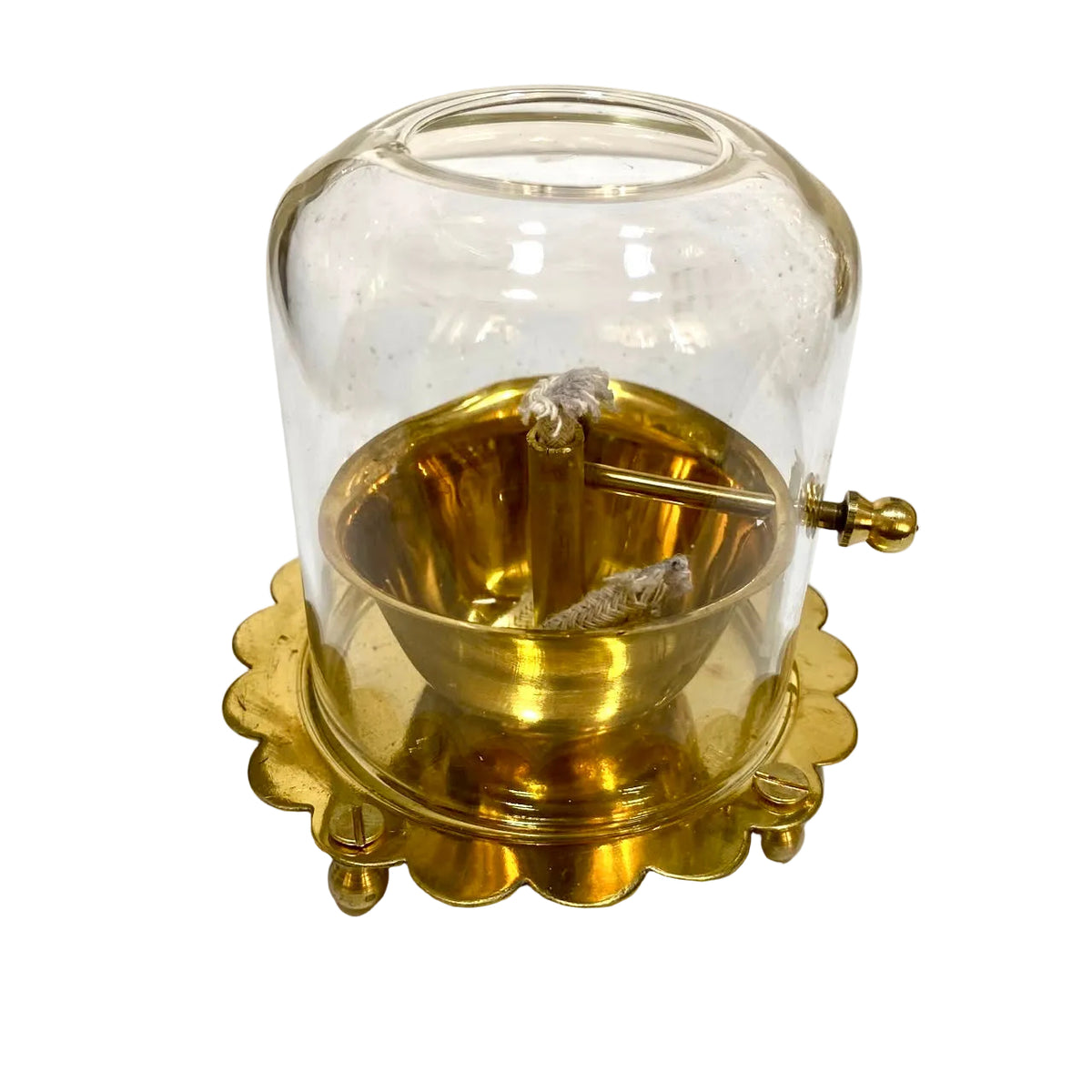 A vintage brass and glass insect trap with a scalloped brass base, a clear glass dome, and a brass bowl containing small dried insects, photographed on a white surface.