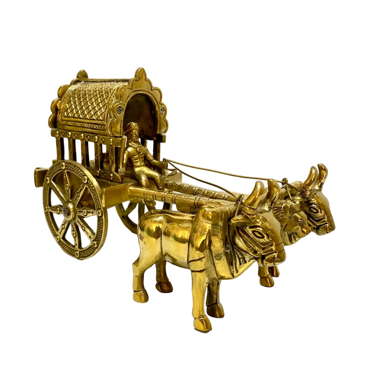 A small brass-colored decorative cart with two oxen, a driver figure, and a detailed roof, photographed against a plain off-white wall and surface.