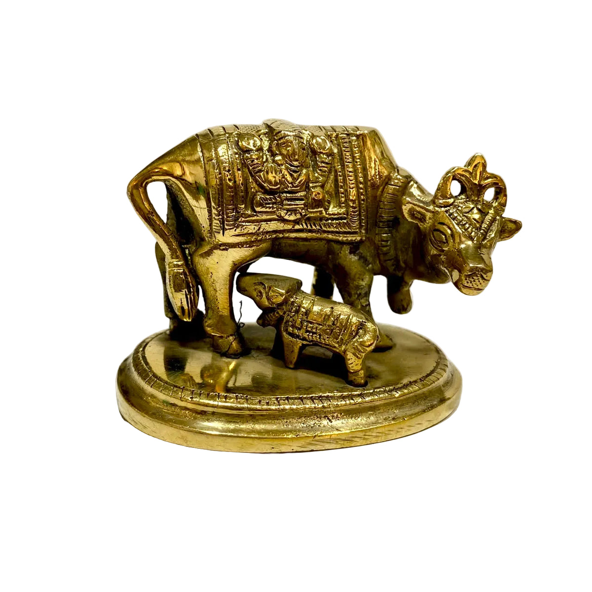 A small brass cow and calf figurine with detailed carvings, standing on an oval base against a plain light background.
