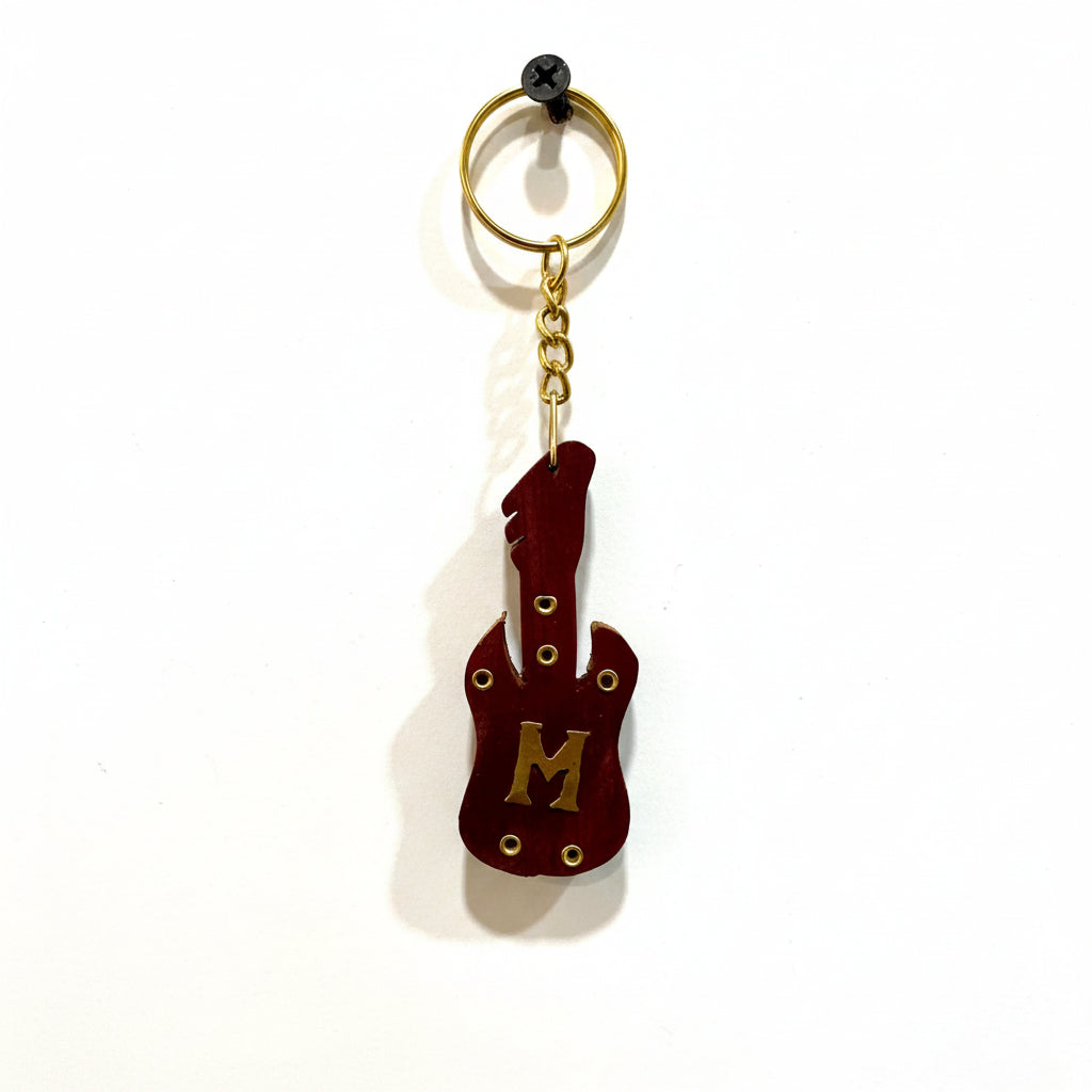 Guitar-shaped keychain with letter 'M' on a textured white background