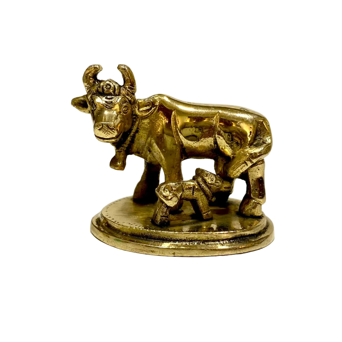 A small brass statue of a cow and calf on a round base, photographed against a plain light background.