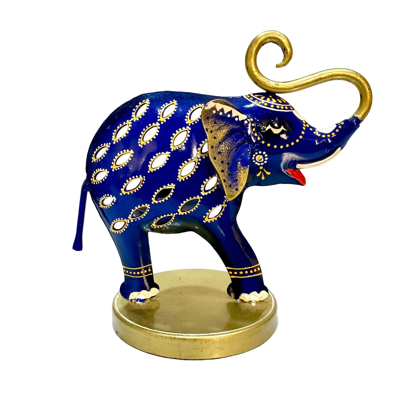 A decorative blue elephant figurine with gold and white paisley-style patterns, a gold trunk curl, and a round gold base, photographed against a light off-white wall and surface.