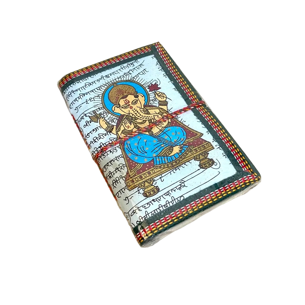 A handmade journal with a colorful hand-painted illustration of Lord Ganesha on the cover, resting on a light wooden table.