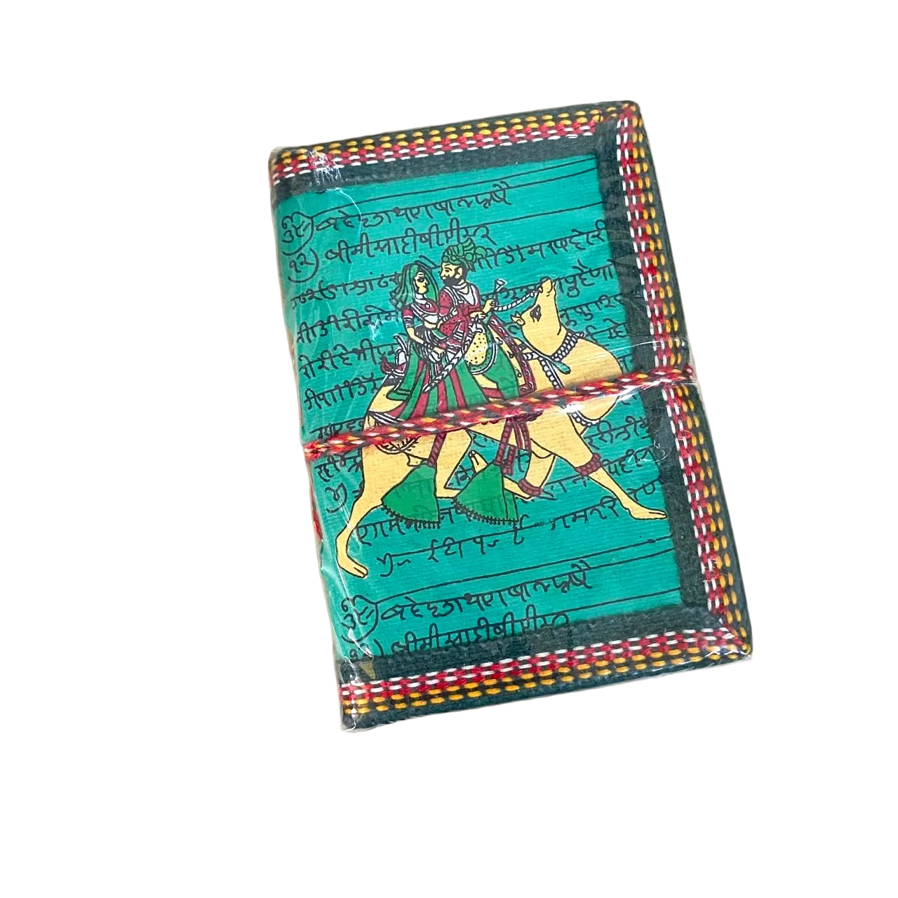 A small handmade notebook or journal with a teal cover, decorated with a hand-painted illustration of a warrior on a yellow horse and handwritten script. It is wrapped with a red and yellow striped elastic band and photographed on a light wood tabletop.