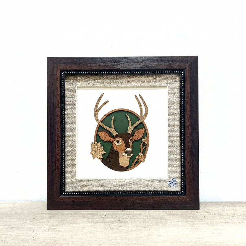 Framed artwork of a deer head with antlers on a textured wall background