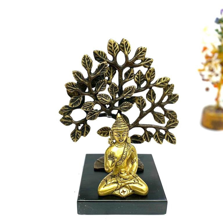 Decorative statue of a seated figure under a tree with branches on a white background