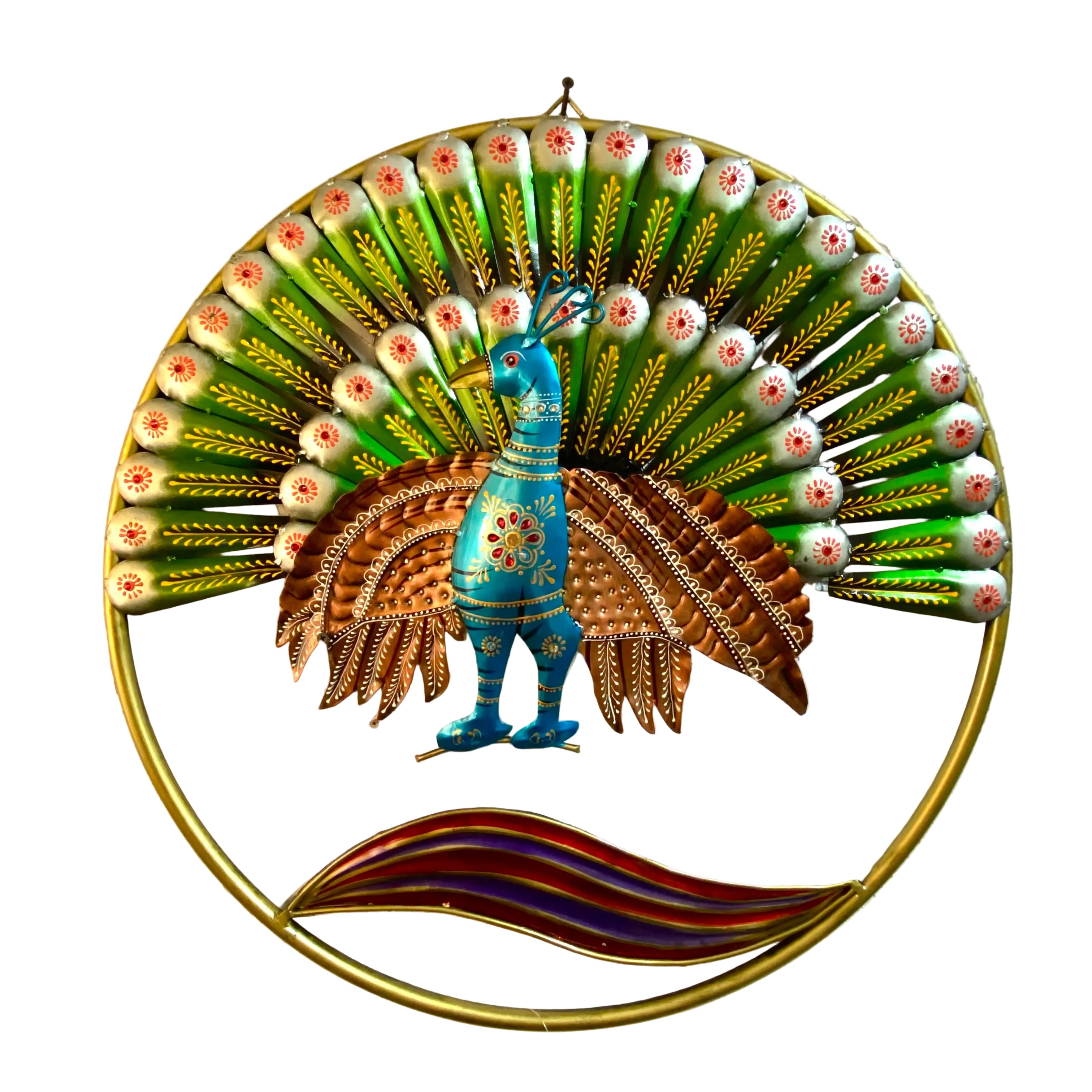 A colorful metal wall art piece depicting a peacock with a large fanned tail, mounted on a textured off-white wall. The peacock is blue and brown with gold accents, set against a green fan of metallic feathers with white and red tips, all enclosed in a gold circular frame with a wavy red and purple stripe at the bottom.