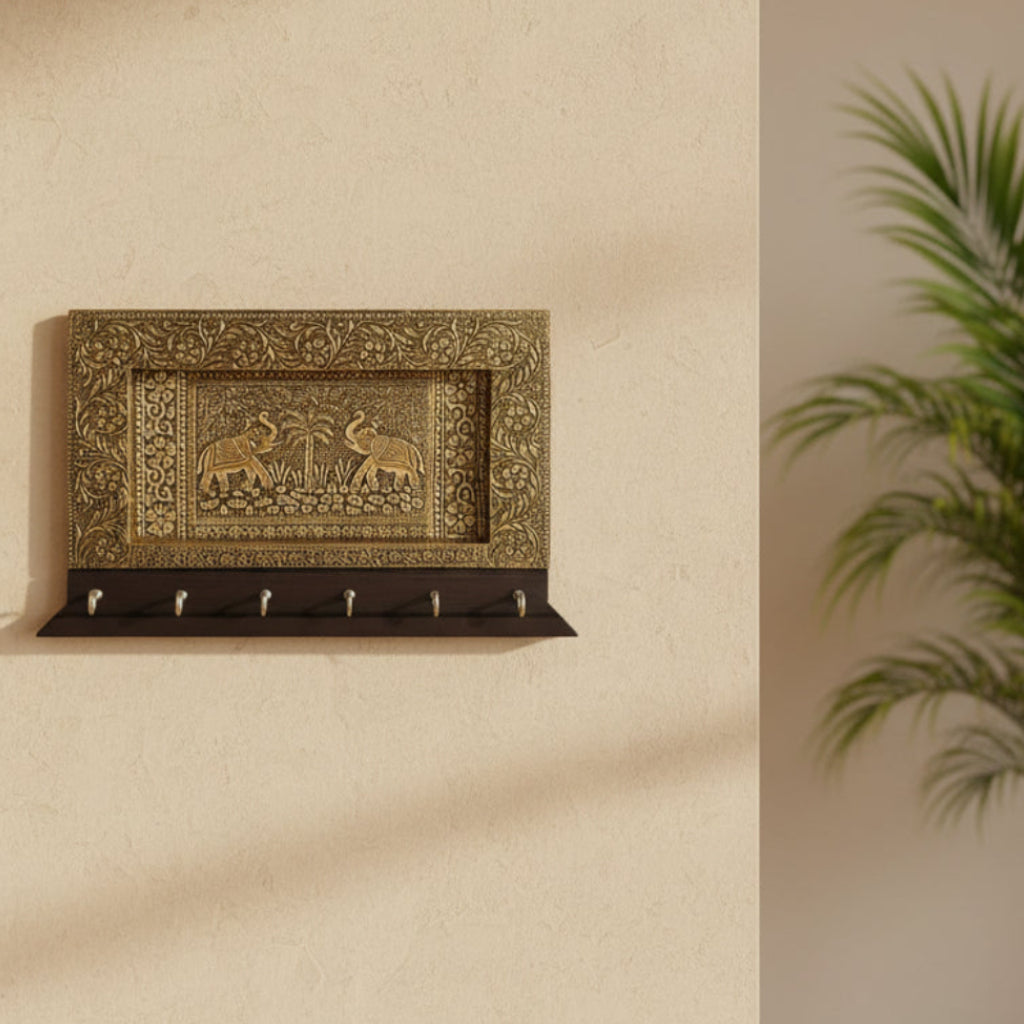 Decorative wall key holder with intricate brass design on a white background
