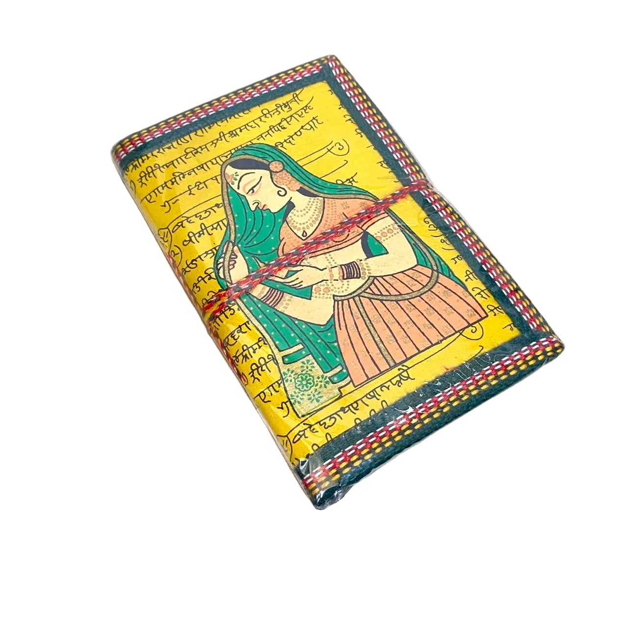 A small handmade notebook or journal with a yellow cover, hand-painted traditional Indian style illustration of a woman, and multicolored stitched edges, lying on a light wooden surface.