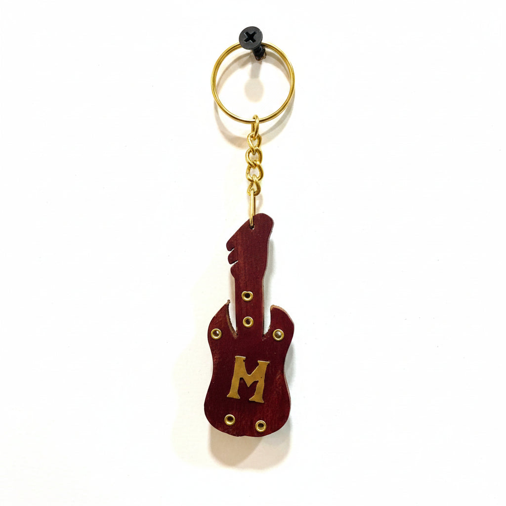 Guitar-shaped keychain with letter 'M' on a textured white background