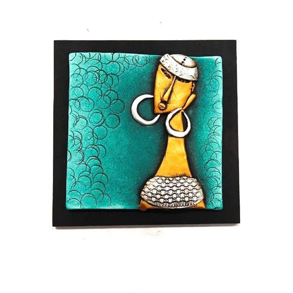 Decorative wall art with a stylized face on a teal background, framed in black.