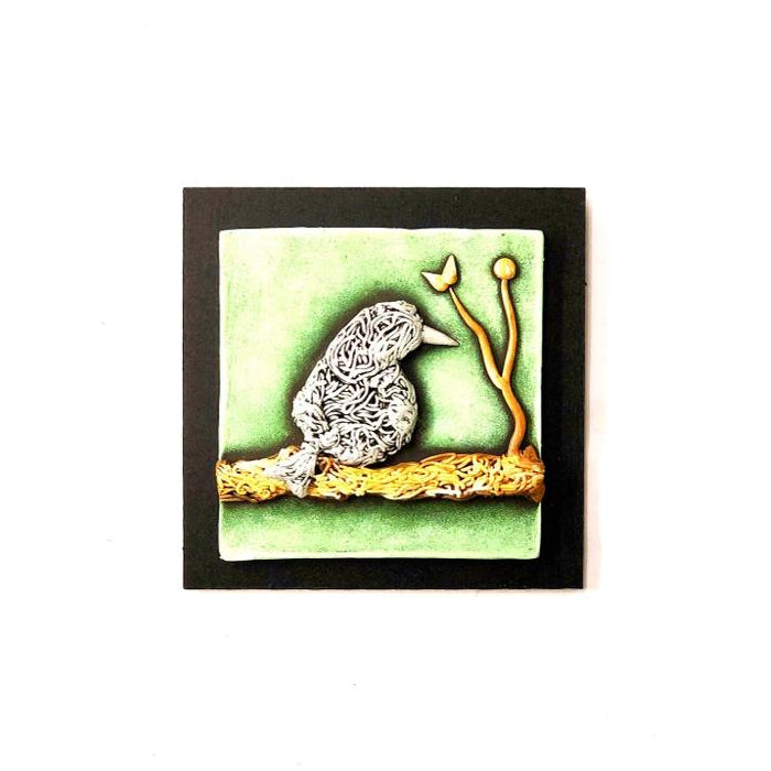 Decorative tile with a bird design on a green background, framed in black.