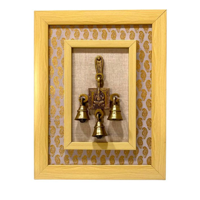 Decorative wall art with a gold frame and three small brass bells on a white background