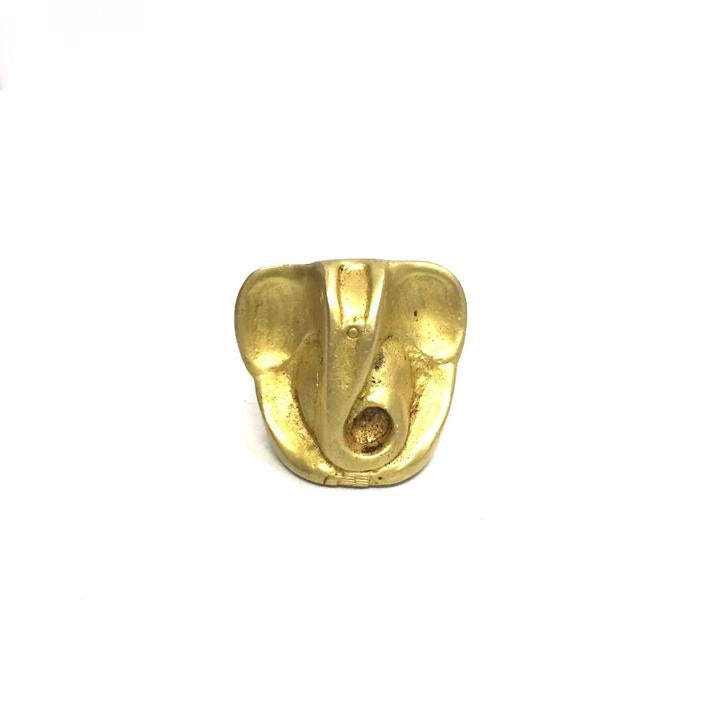 A brass idol of Ganesh in a sitting position with a gold-colored finish on a white background.